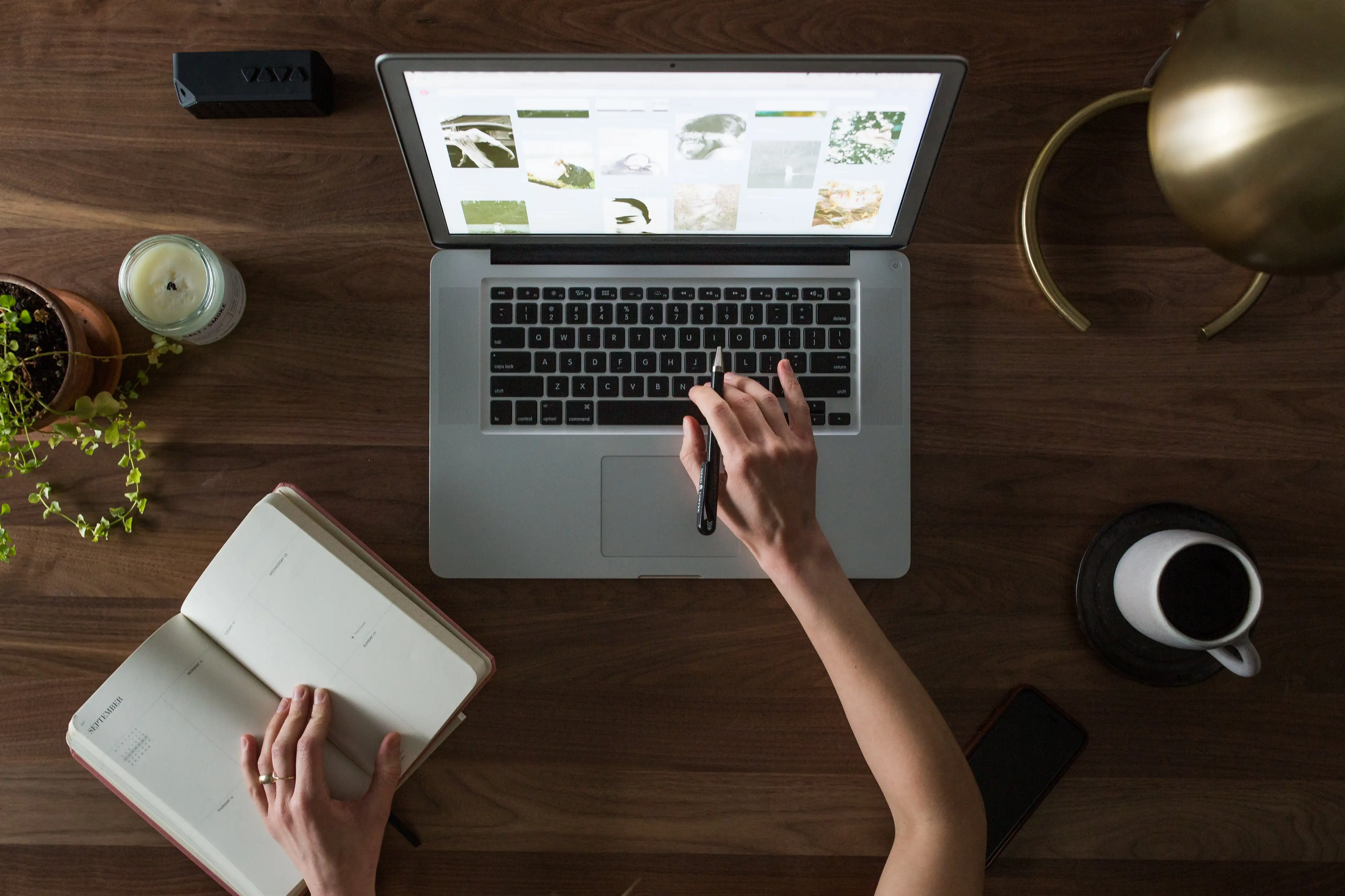 Image représentant une personne avec un cahier et un ordinateur portable sur son bureau.